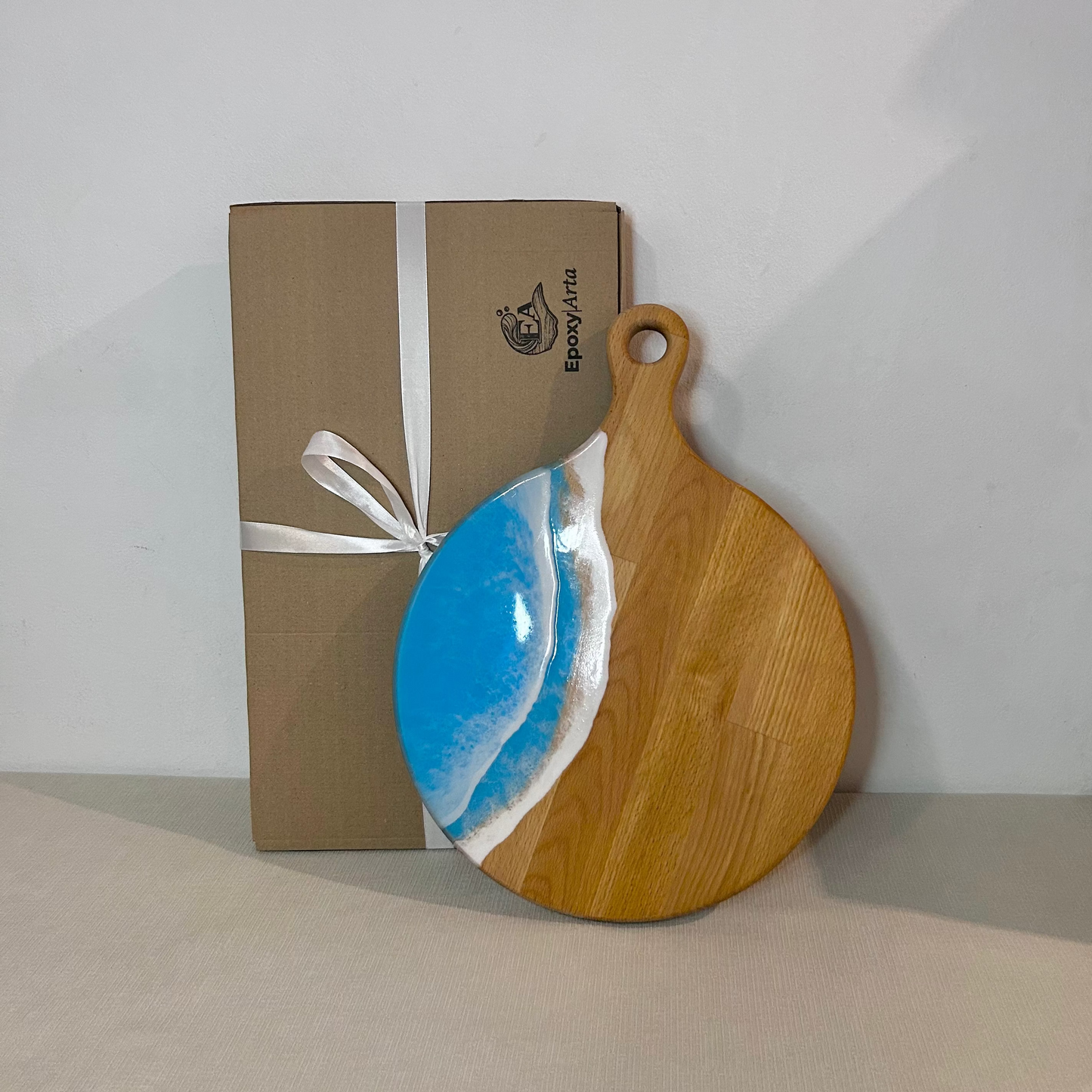 Platou / tocator rotund cu maner din lemn de fag cu rasina epoxidica, efect ocean albastru deschis. Personalizata cu un mesaj ales de tine - epoxyarta.ro